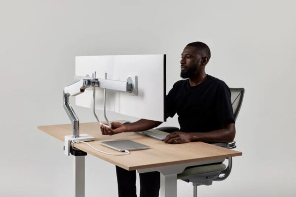 Ergonomiczne ramiona do monitorów Humanscale na nowoczesnym stanowisku pracy.